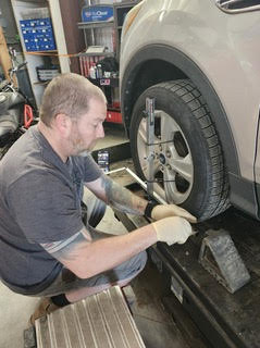 A mechanic checks the alignment of a vehicle's tire in a garage, using a tool for precise measurement. This image highlights automotive maintenance skills.