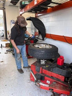 A technician uses a tire machine to mount a tire onto a wheel in a well-lit automotive shop, showcasing tire maintenance procedures.